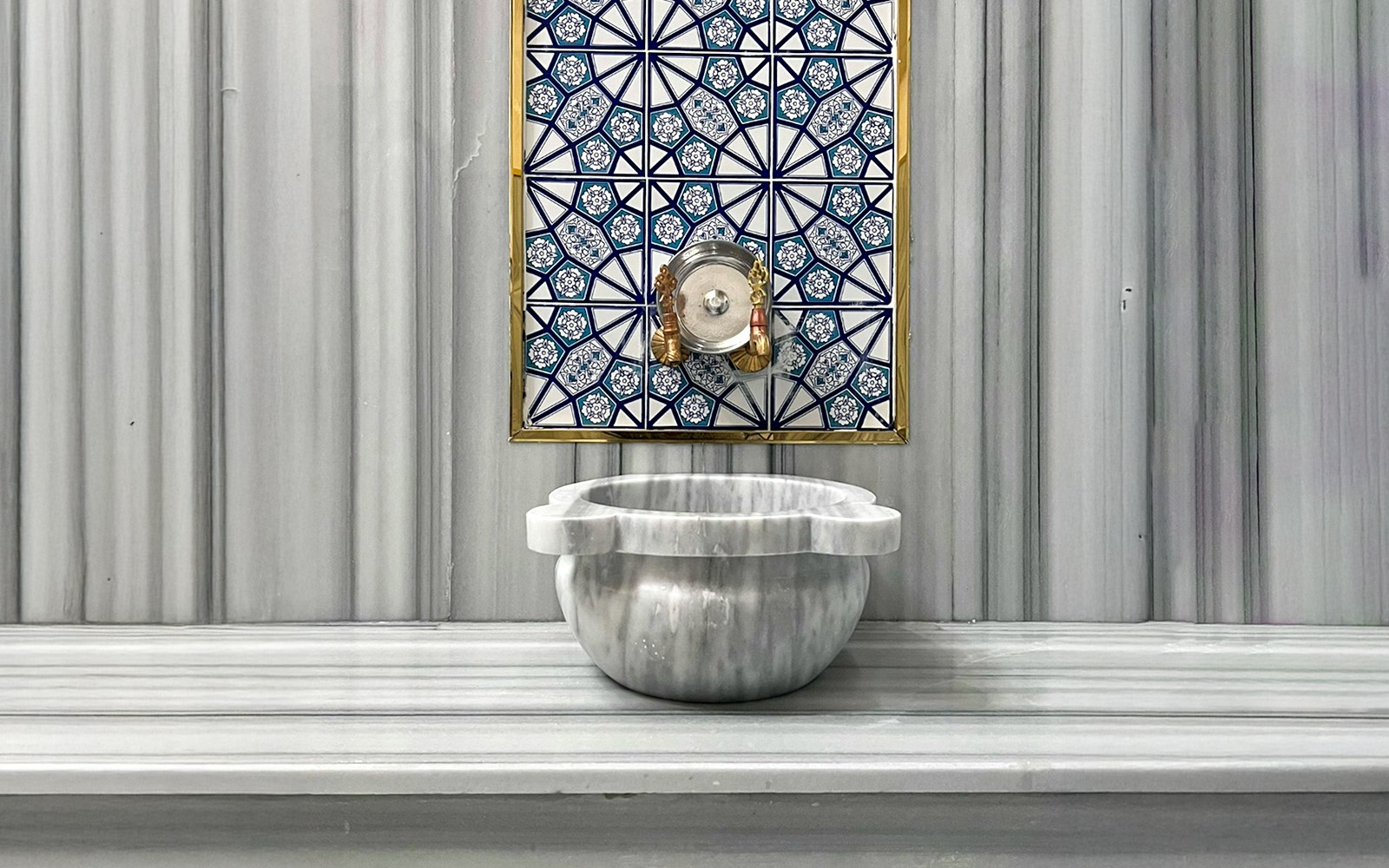 Marble basin and ornate tile wall inside Sifa Hamam.