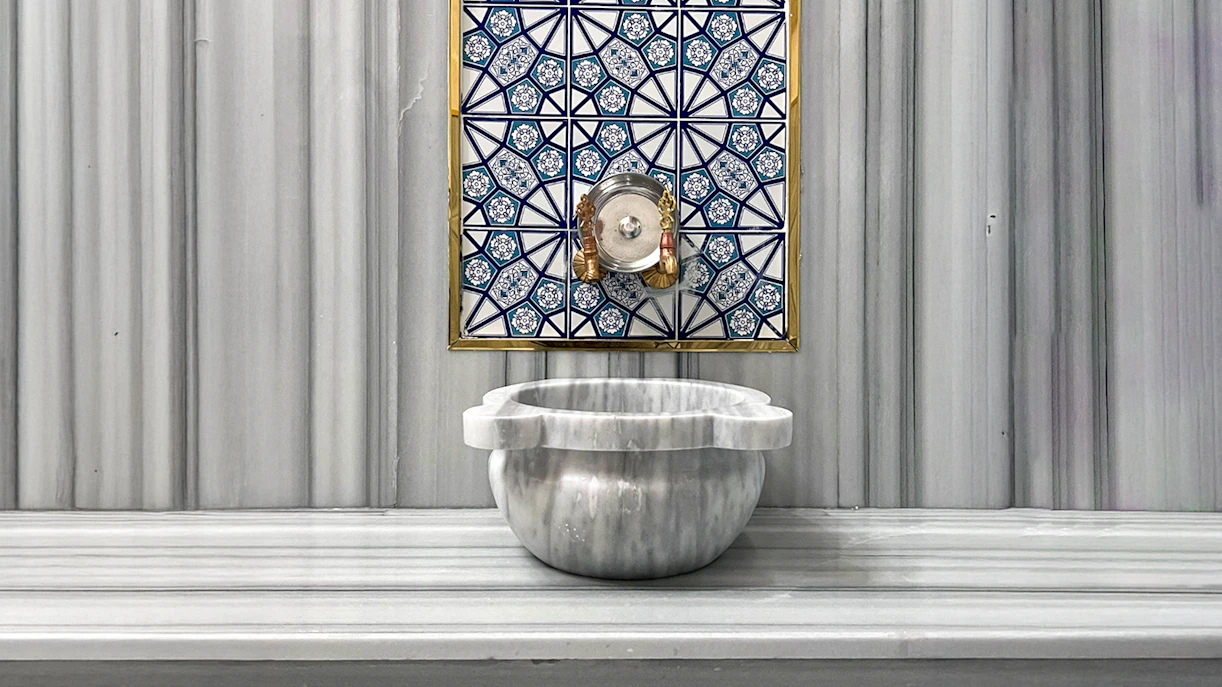 Marble basin and ornate tile wall inside Sifa Hamam.
