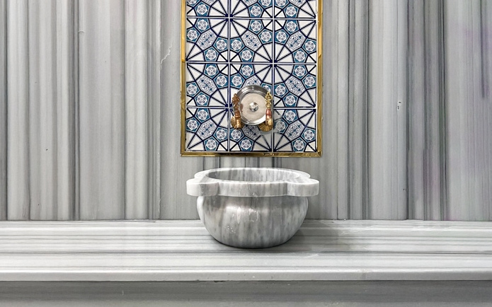 Marble basin and ornate tile wall inside Sifa Hamam.