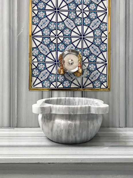 Marble basin and ornate tile wall inside Sifa Hamam.