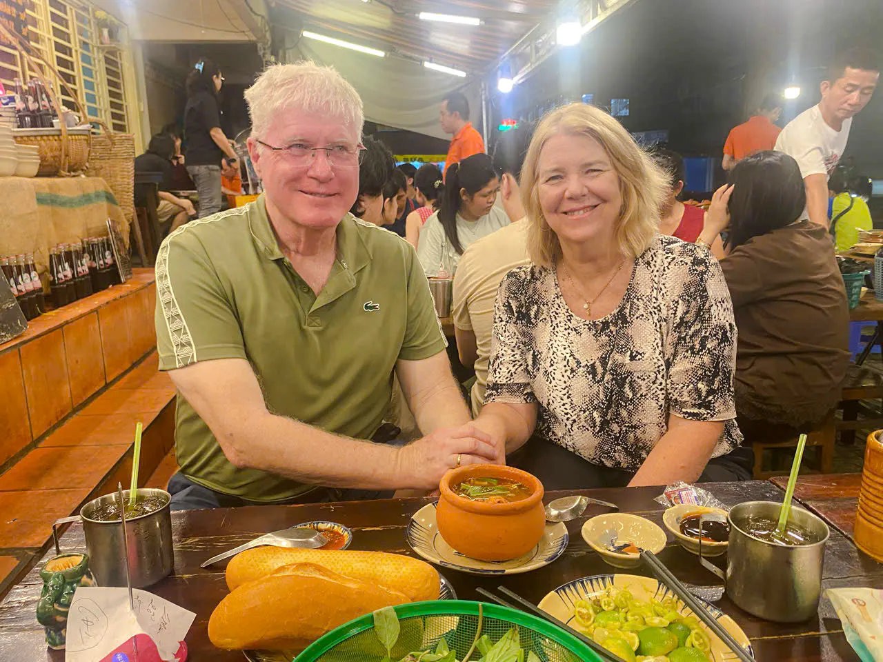 Couple enjoying local cuisine at a bustling street food market in Ho Chi Minh City.