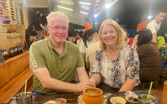Couple enjoying local cuisine at a bustling street food market in Ho Chi Minh City.