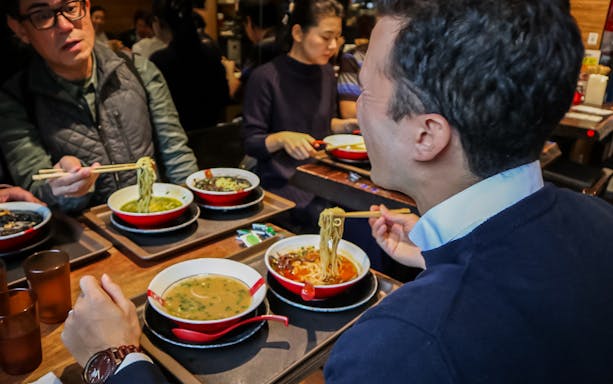 People enjoying a Tokyo ramen tasting tour with six mini bowls of ramen.