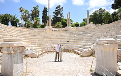 Roman amphitheater in Alexandria, Egypt, with tourists exploring the ancient site.