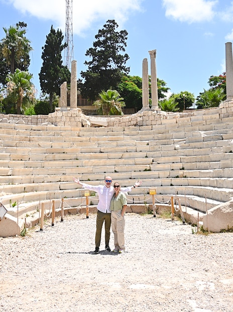 Roman amphitheater in Alexandria, Egypt, with tourists exploring the ancient site.