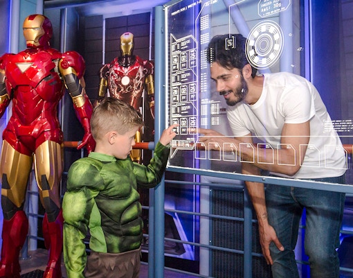 Child in Hulk costume interacting with Iron Man display at Madame Tussauds Amsterdam.