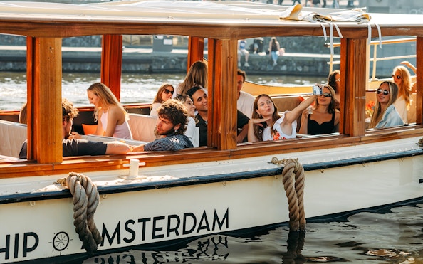 Guests enjoying a canal cruise with cheese and wine in Amsterdam.