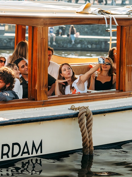 Guests enjoying a canal cruise with cheese and wine in Amsterdam.