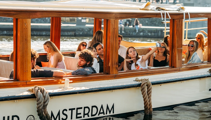 Guests enjoying a canal cruise with cheese and wine in Amsterdam.