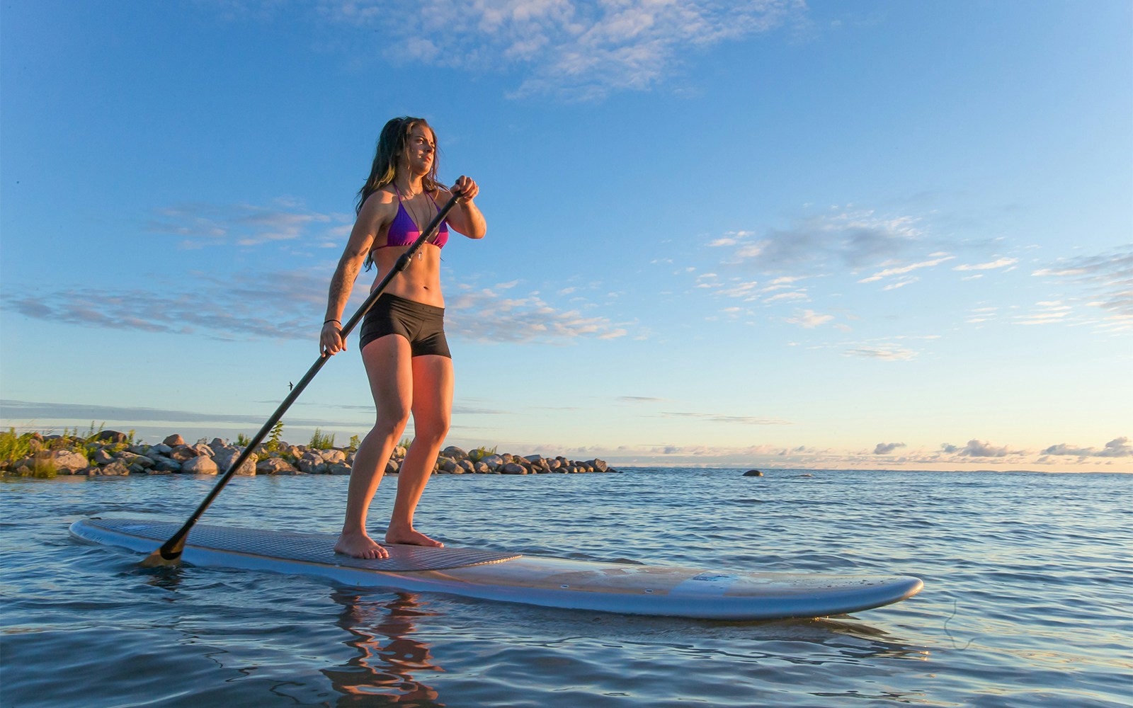 Female paddleboarding at sunrise on Moreton Island, Australia.