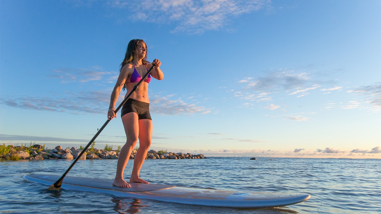 Female paddleboarding at sunrise on Moreton Island, Australia.