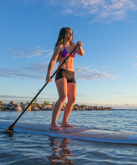 Female paddleboarding at sunrise on Moreton Island, Australia.