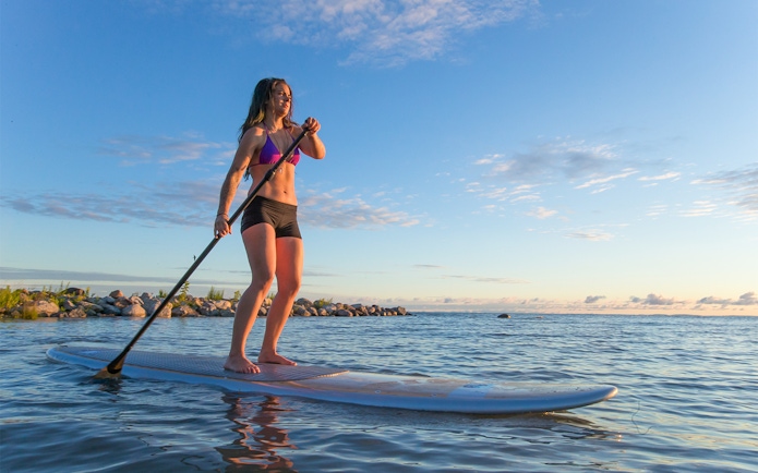 Female paddleboarding at sunrise on Moreton Island, Australia.