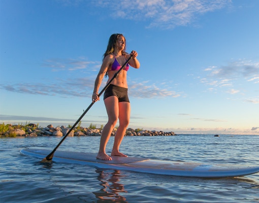 Female paddleboarding at sunrise on Moreton Island, Australia.