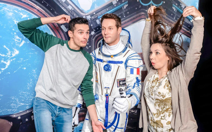 Visitors posing with astronaut figure at Grévin Wax Museum, Paris.
