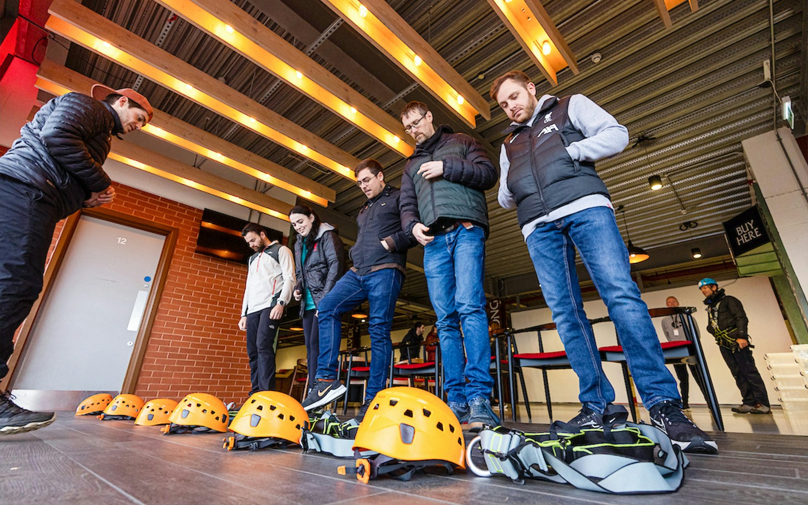 Visitors preparing for Anfield abseil with helmets and harnesses at Liverpool FC Stadium.