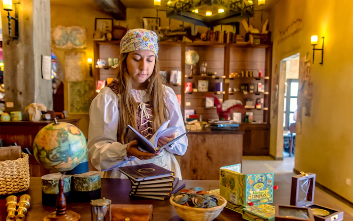 Performer in historical costume reading a book at Puy du Fou España park.