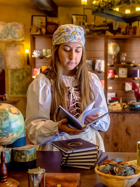 Performer in historical costume reading a book at Puy du Fou España park.
