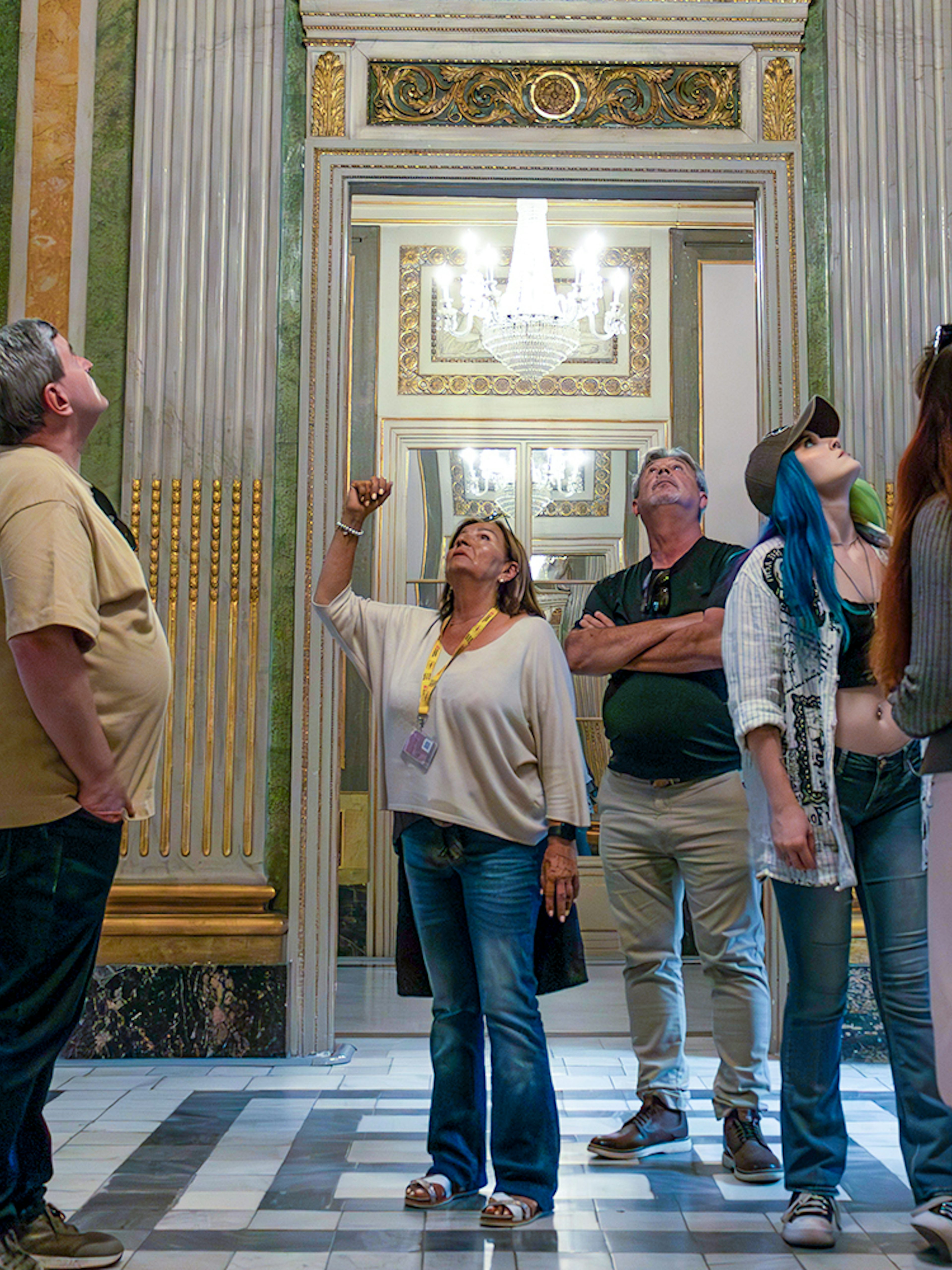 Visitors on a guided tour in the Picasso Museum, observing ornate sculptures and decor.