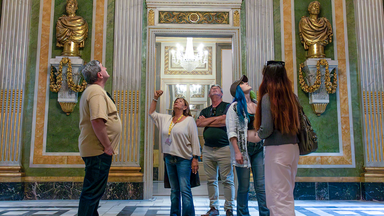 Visitors on a guided tour in the Picasso Museum, observing ornate sculptures and decor.