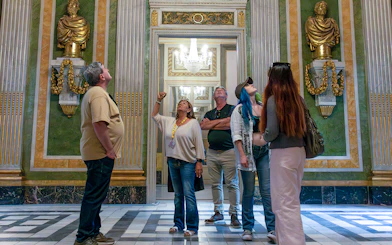Visitors on a guided tour in the Picasso Museum, observing ornate sculptures and decor.