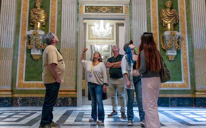 Visitors on a guided tour in the Picasso Museum, observing ornate sculptures and decor.