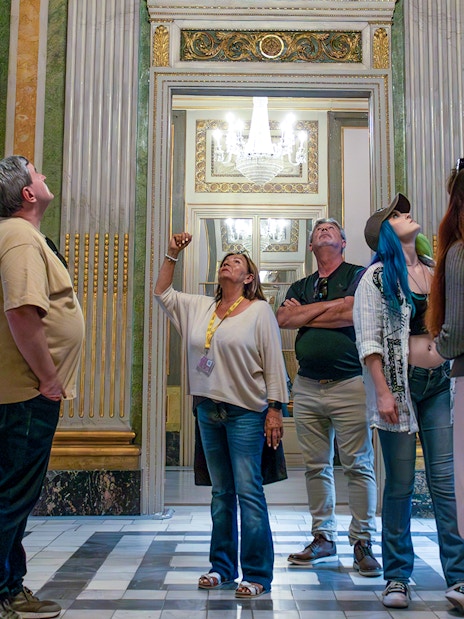 Visitors on a guided tour in the Picasso Museum, observing ornate sculptures and decor.
