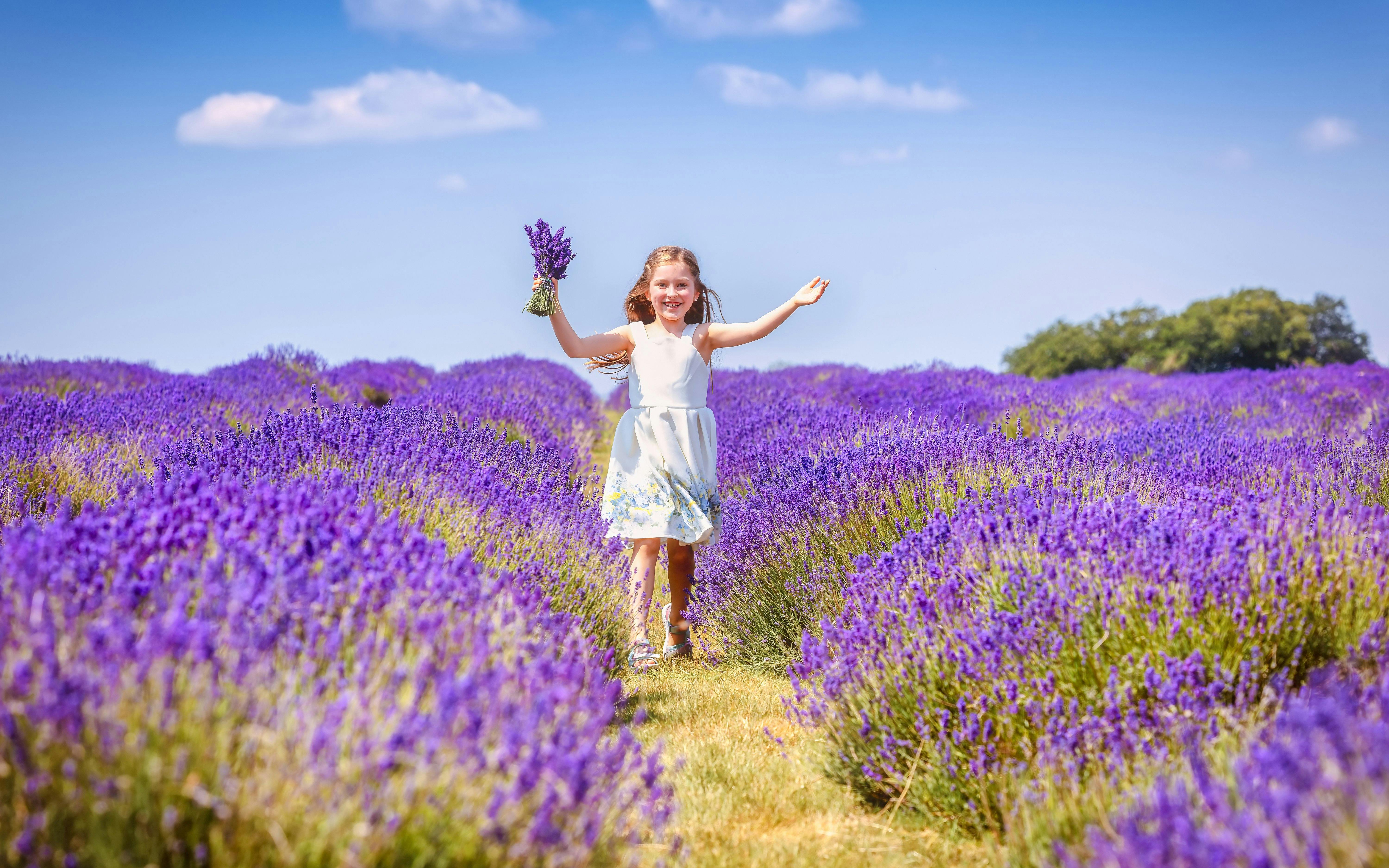 Child running through lavender fields holding flowers.