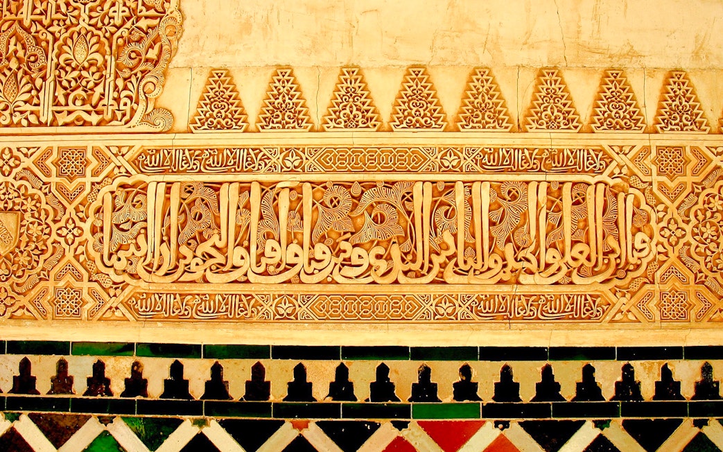 Alhambra's intricate Islamic calligraphy and geometric patterns in Granada, Spain.