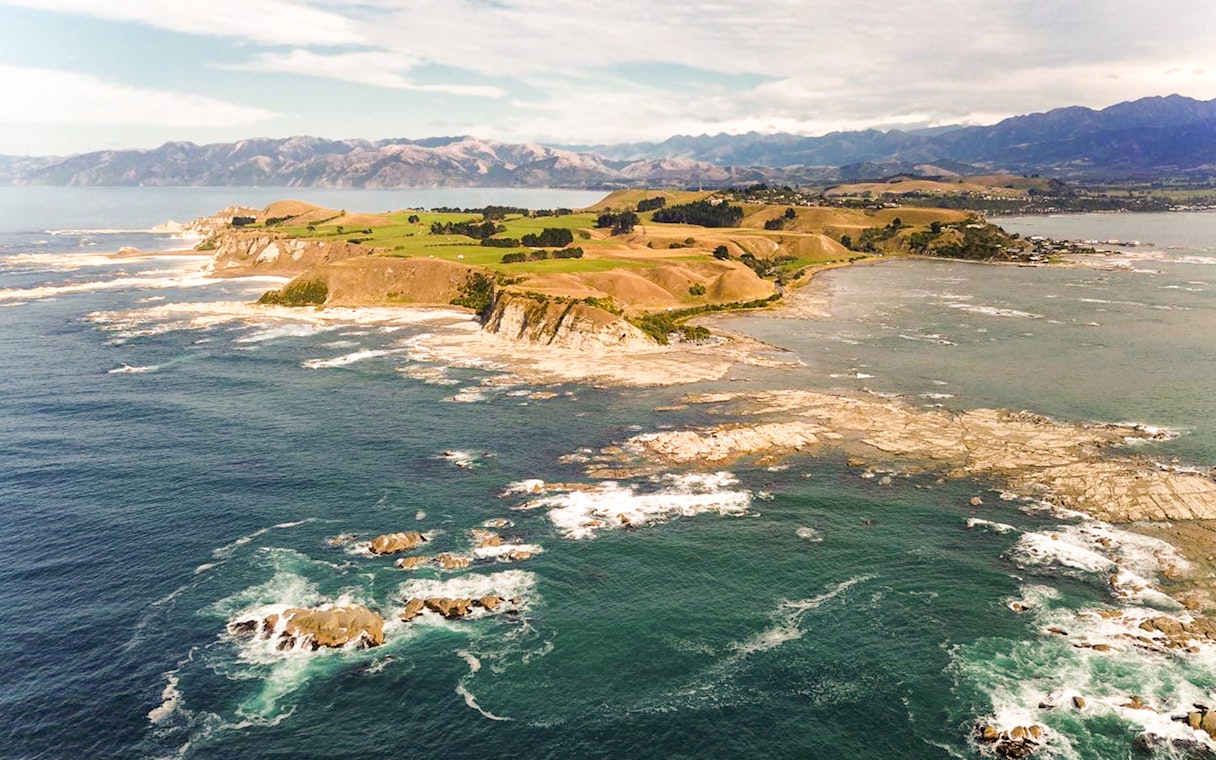 Aerial view of Kaikoura coastline with rocky shores and distant mountains.