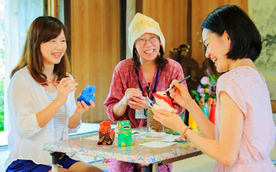Visitors painting traditional crafts at Ishigaki Yaima Village workshop.