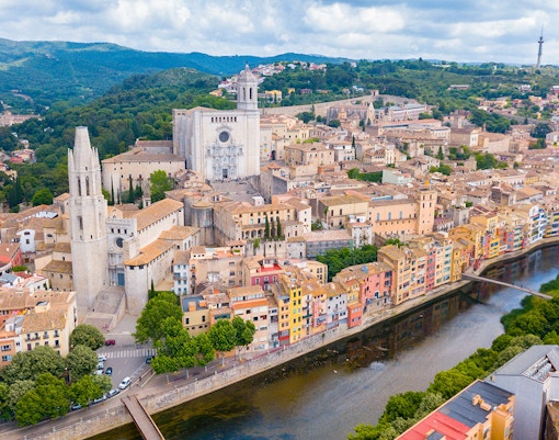 Aerial view of Girona Cathedral, St. Feliu Church, and colorful houses along the Onyar River in Girona, Spain.