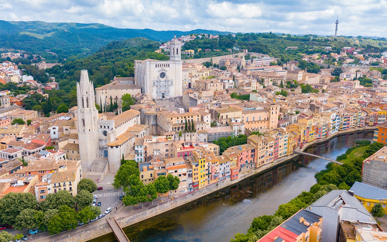 Aerial view of Girona Cathedral, St. Feliu Church, and colorful houses along the Onyar River in Girona, Spain.