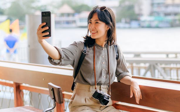 Tourist using smartphone with Japan 3G eSIM card by a riverside.