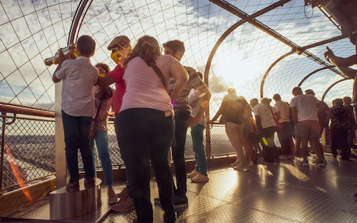 Visitors enjoying the view from the Eiffel Tower summit during a small-group tour.