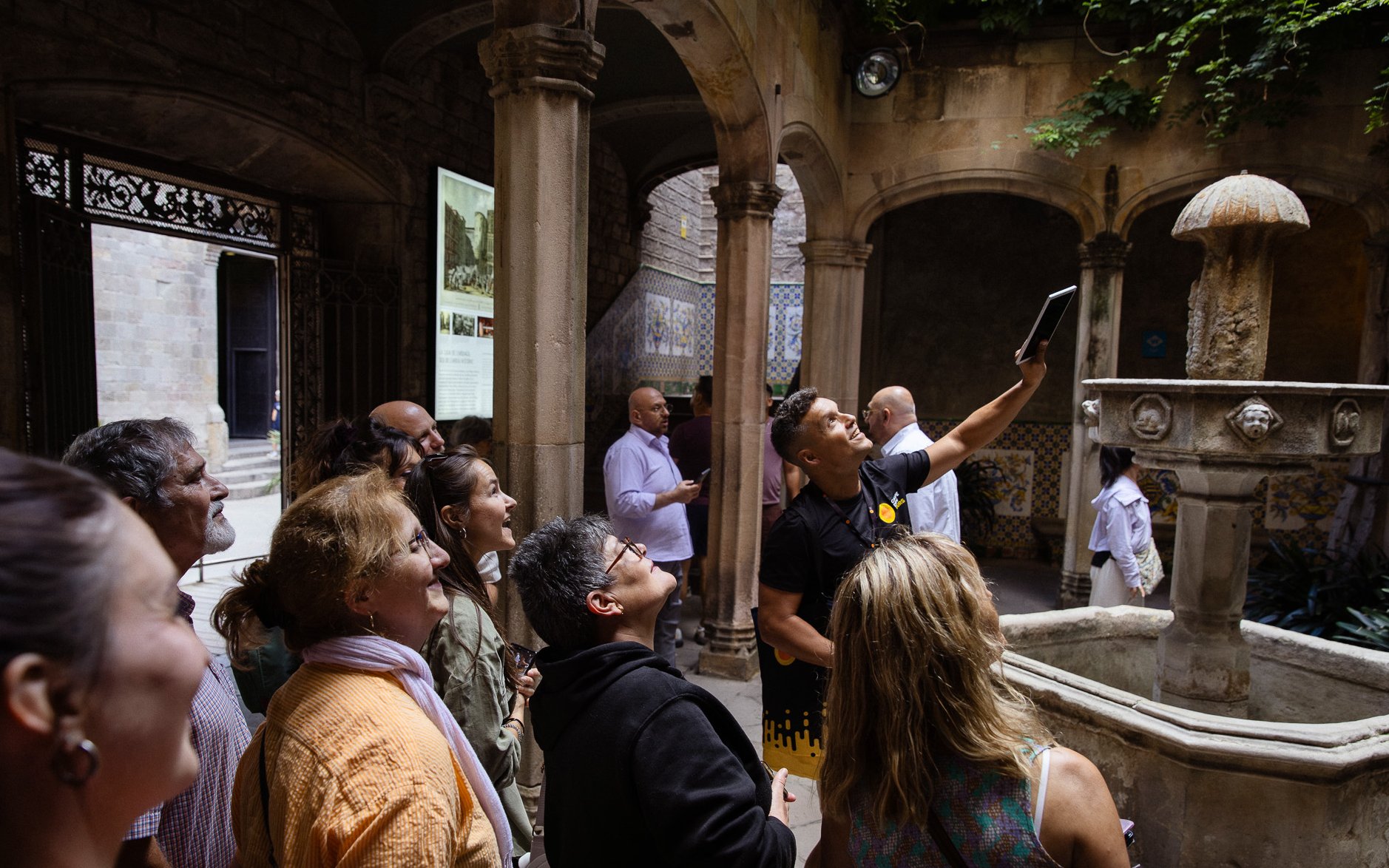 Tourists listening to a guide in a historic courtyard in Barcelona.