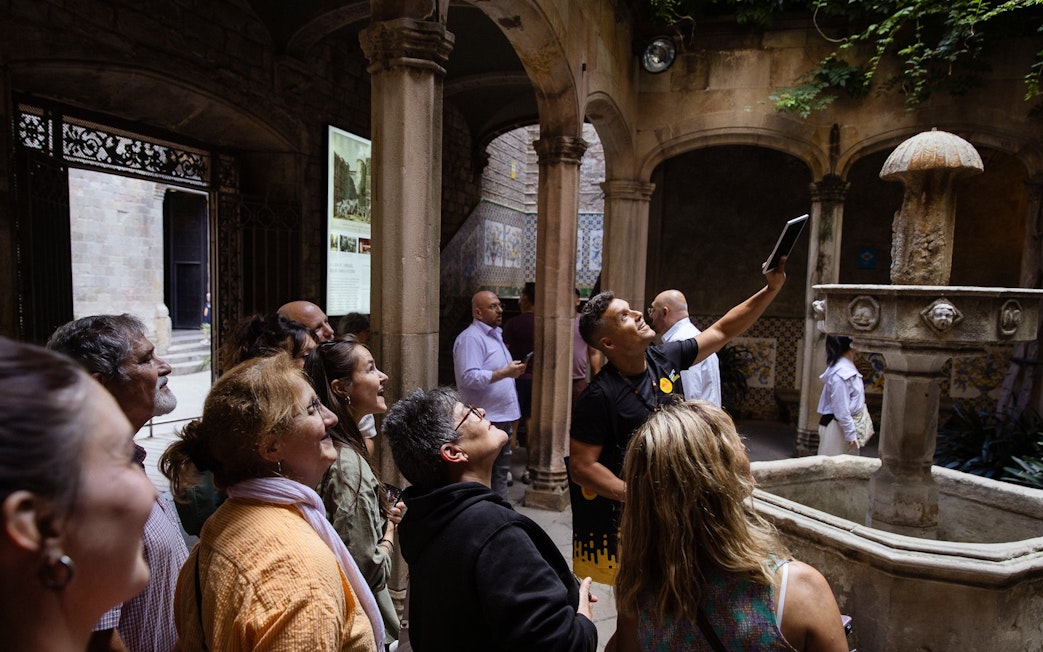 Tourists listening to a guide in a historic courtyard in Barcelona.