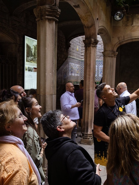 Tourists listening to a guide in a historic courtyard in Barcelona.