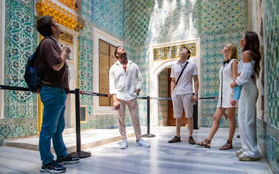 Visitors exploring ornate tilework in Topkapi Palace Museum's Harem, Istanbul.