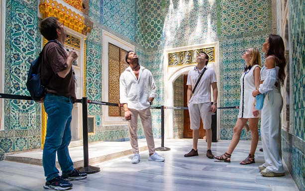 Visitors exploring ornate tilework in Topkapi Palace Museum's Harem, Istanbul.