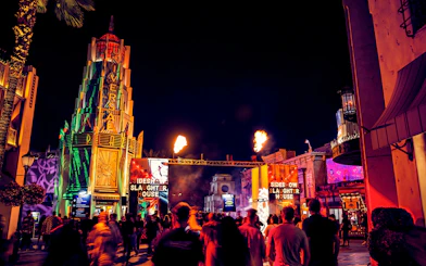 Crowds at Hollywood Horror Nights, Universal Studios Hollywood, with fiery entrance and neon lights.