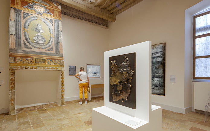 Visitor viewing art inside Beaulieu-en-Rouergue Abbey, France.