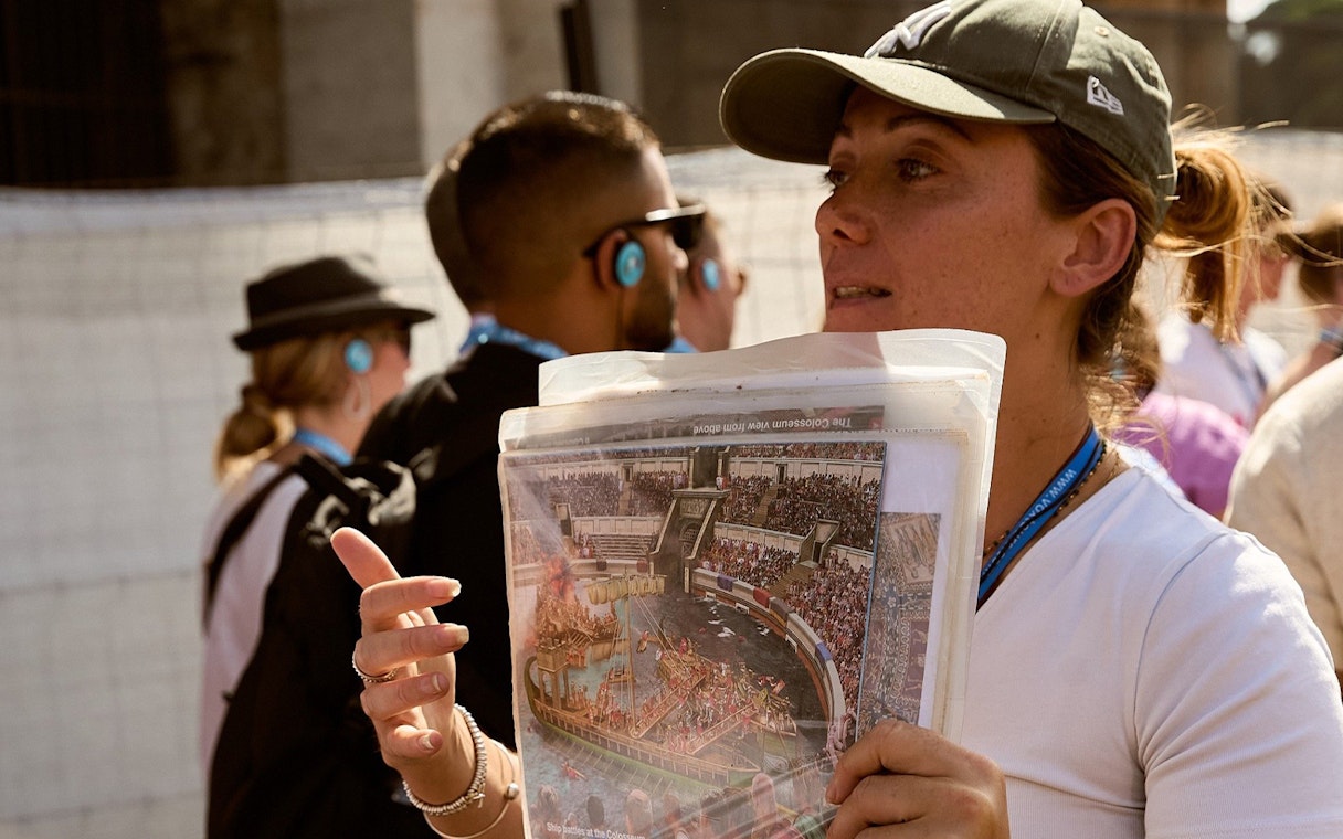 Guide explaining Colosseum history to tourists in Rome.
