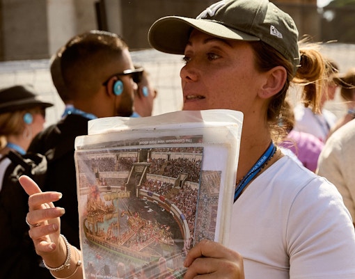 Guide explaining Colosseum history to tourists in Rome.
