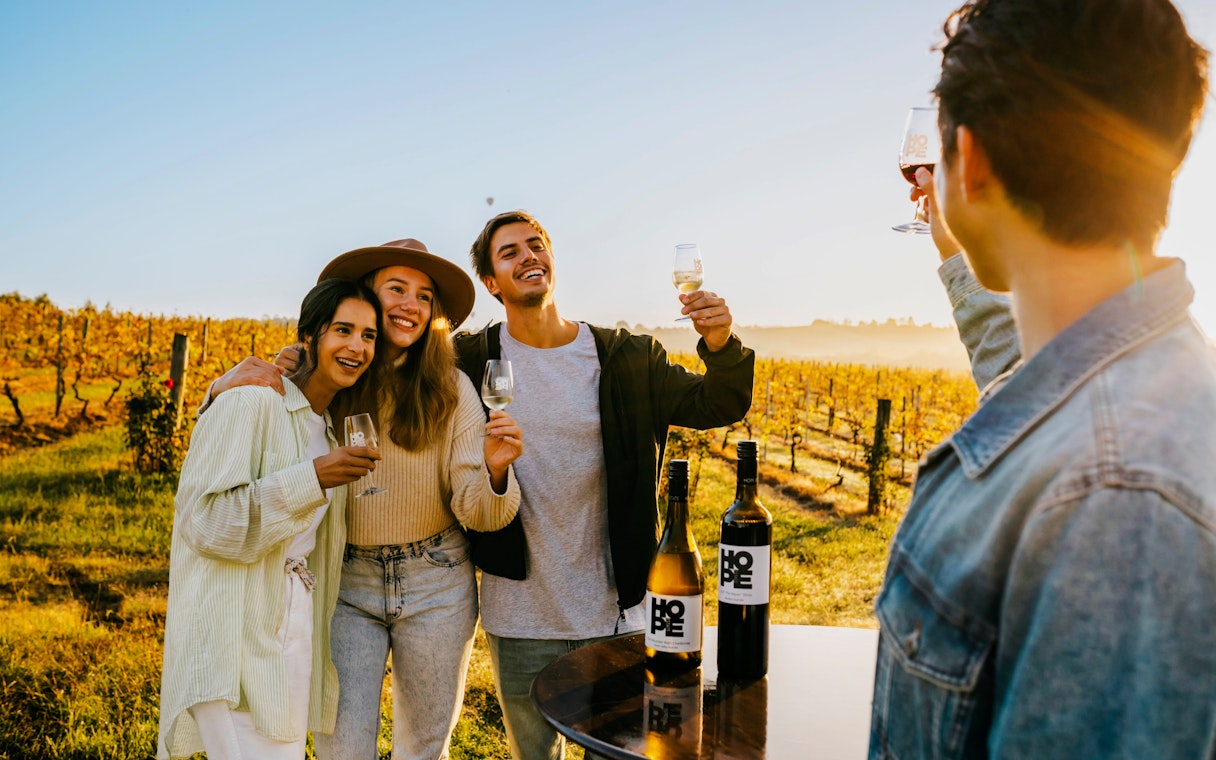 Group enjoying wine tasting at a vineyard estate during sunset.