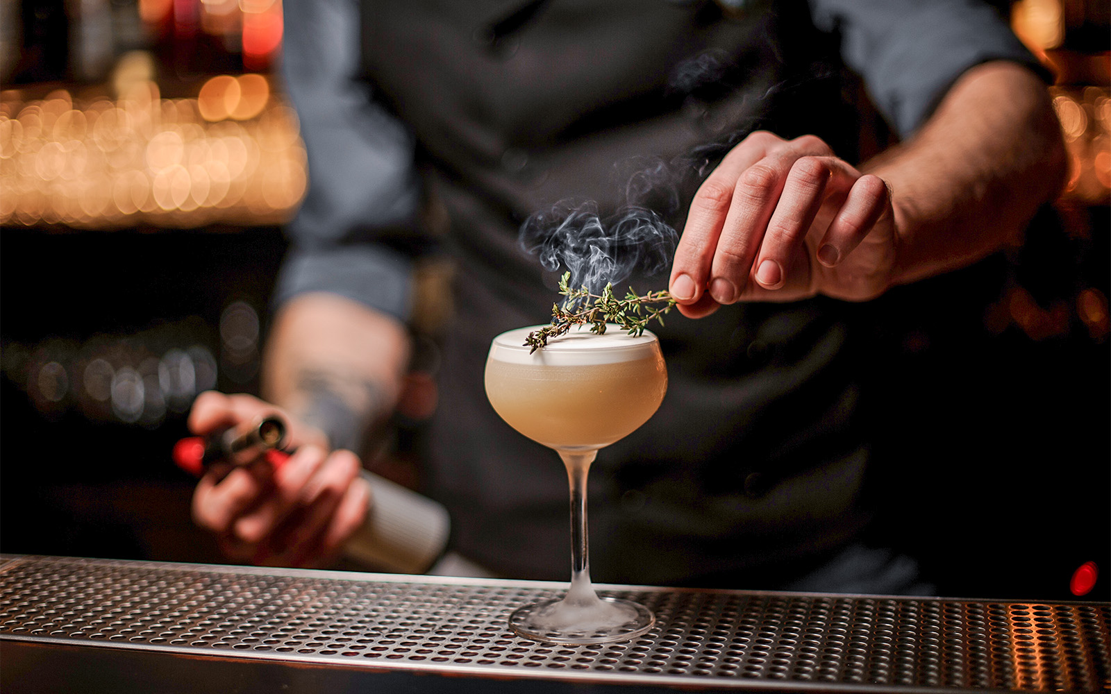 Bartender garnishing a cocktail with herbs at a Singapore bar in October.