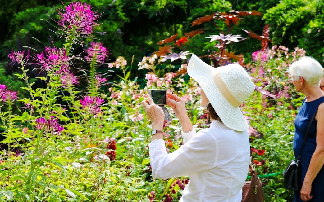 Visitors photographing vibrant flowers at Claude Monet’s gardens in Giverny.