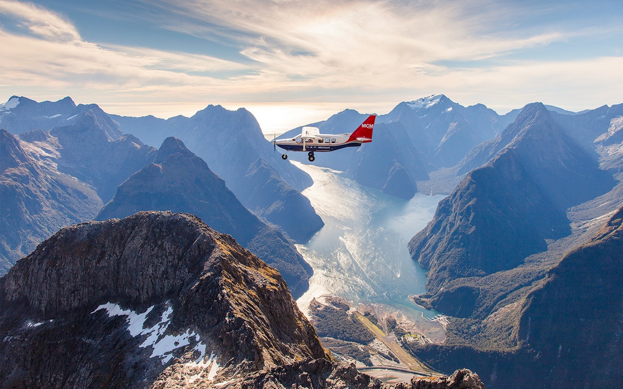 Aerial view of Milford Sound with a cruise ship below, scenic flyover from Queenstown.