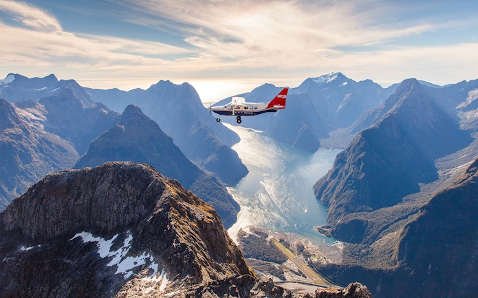 Aerial view of Milford Sound with a cruise ship below, scenic flyover from Queenstown.