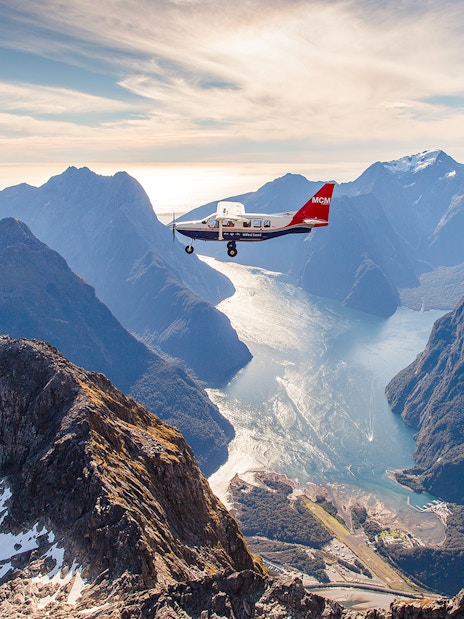Aerial view of Milford Sound with a cruise ship below, scenic flyover from Queenstown.